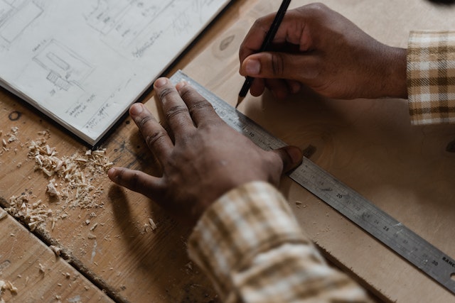 maintenance worker marking measurements on a piece of wood